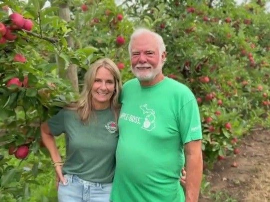 Bruce and his wife standing together in the MacIntosh Orchards apple rows