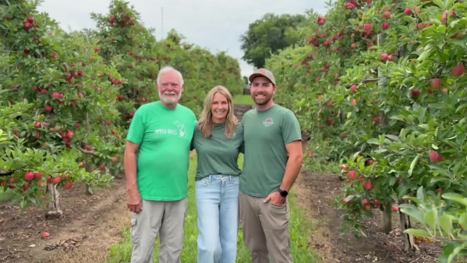 The Macintosh Orchards family standing together in the orchard rows