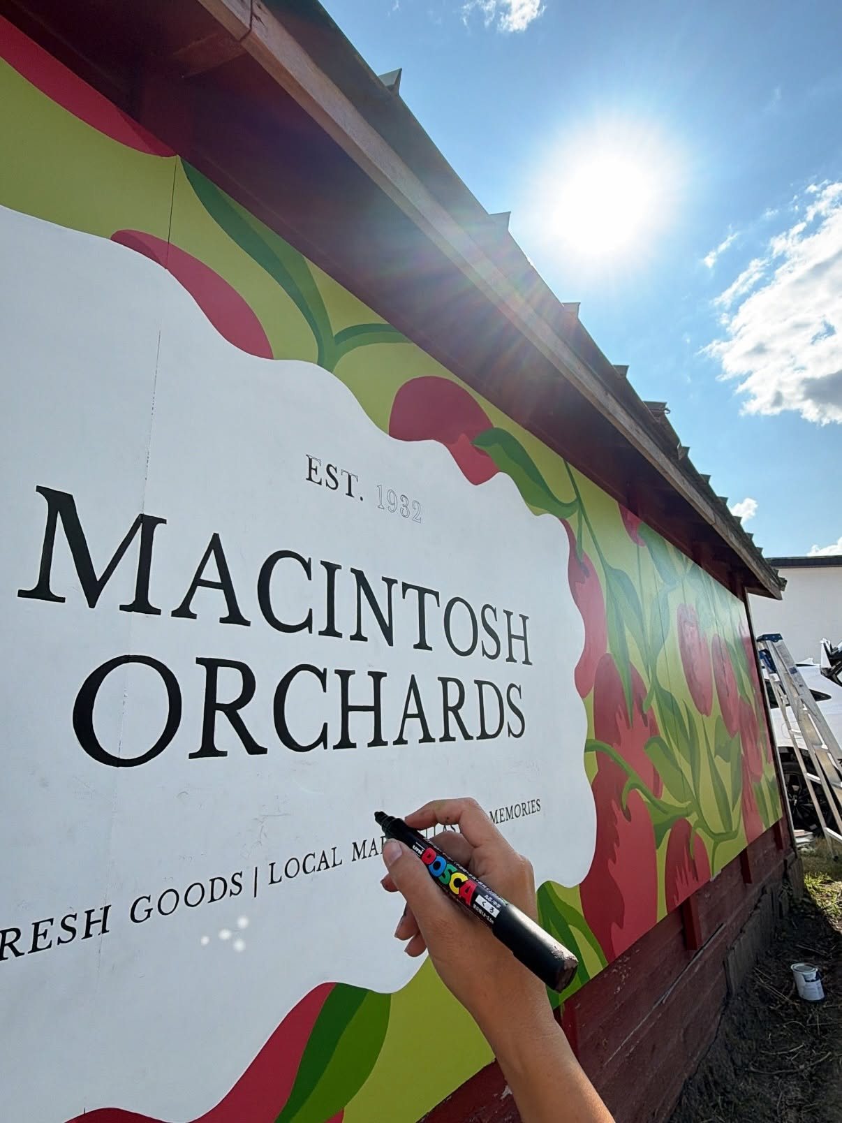 Hand lettering the Macintosh Orchards sign onto the mural with a paint marker