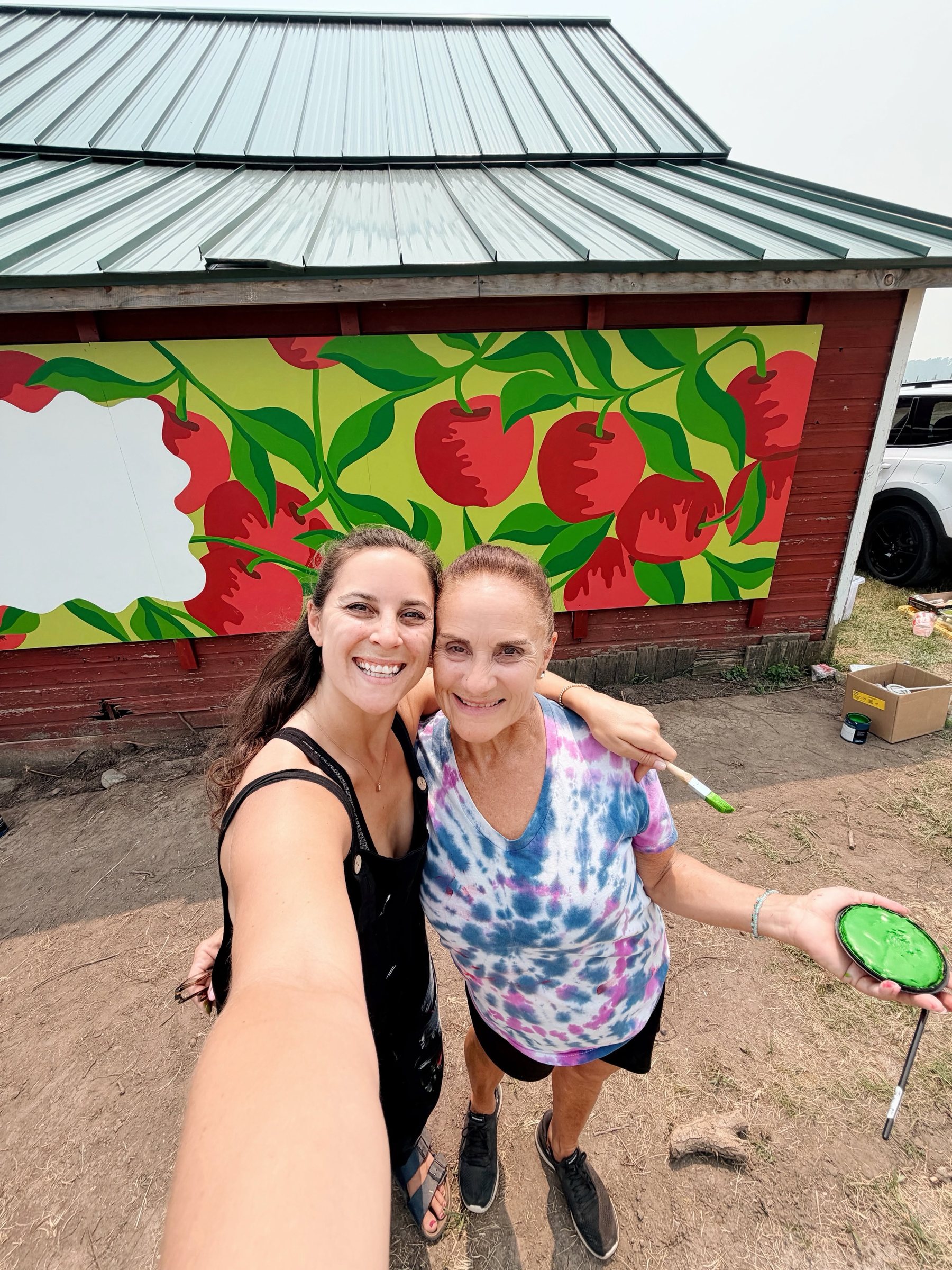 Crystalle Mercedes and a helper celebrating in front of the finished Macintosh Orchards mural